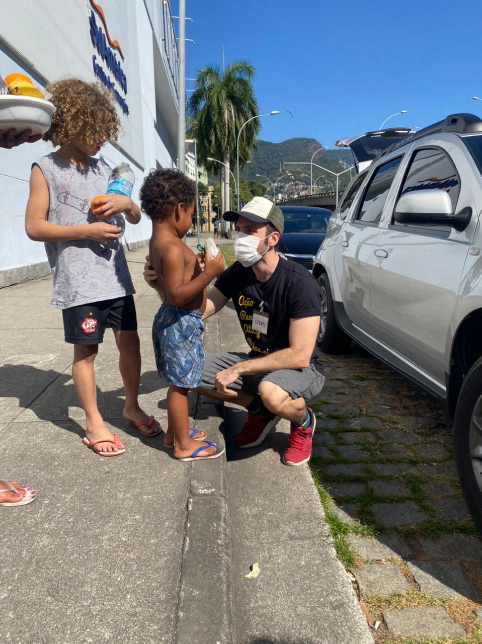 Voluntário do projeto Só Vamos entregando alimento a crianças